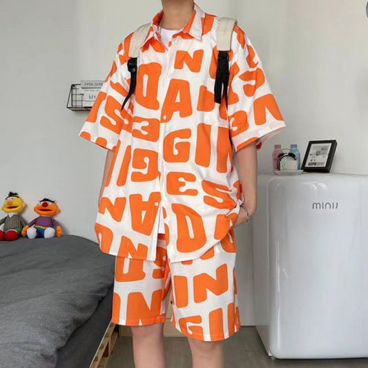 Person wearing a white outfit with orange text patterns in a room.
