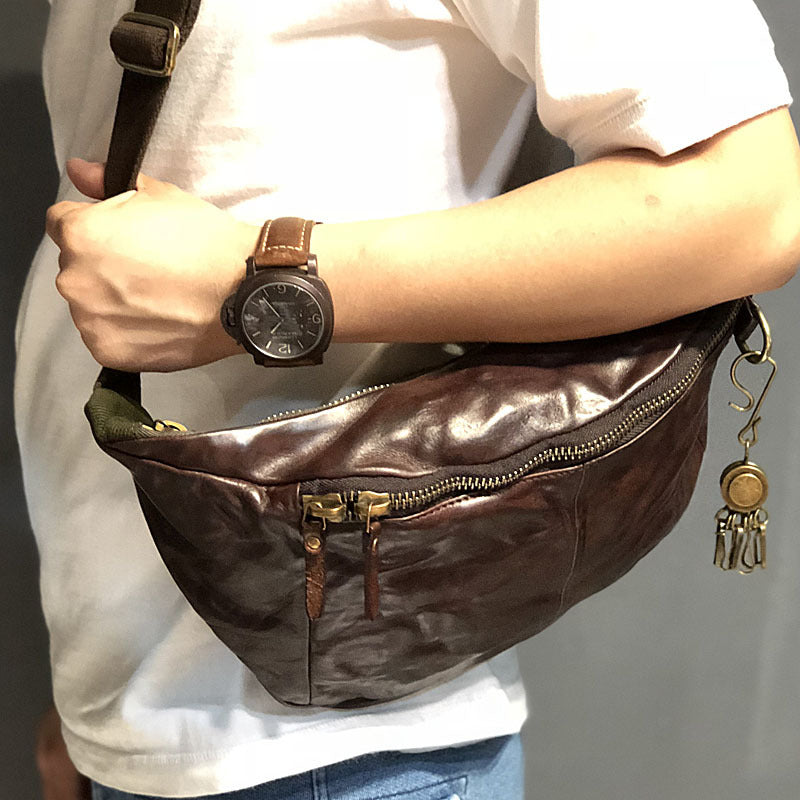 Brown leather bag with a person holding it, wearing a watch on their wrist.