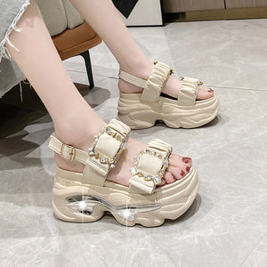 Beige platform sandals with decorative straps on a light gray floor.