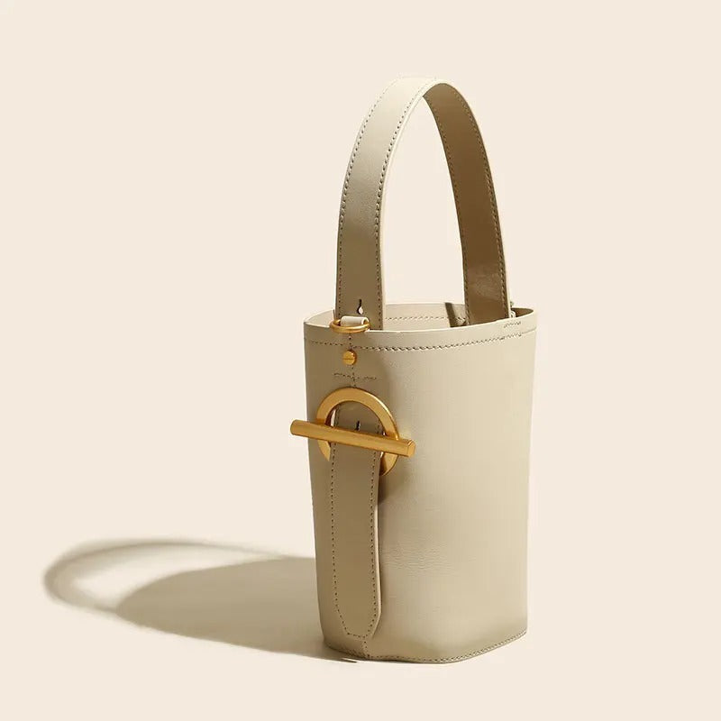 Beige handbag with a gold clasp on a beige background