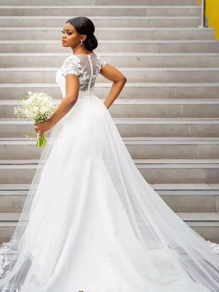 Woman in a white wedding dress holding flowers on a staircase