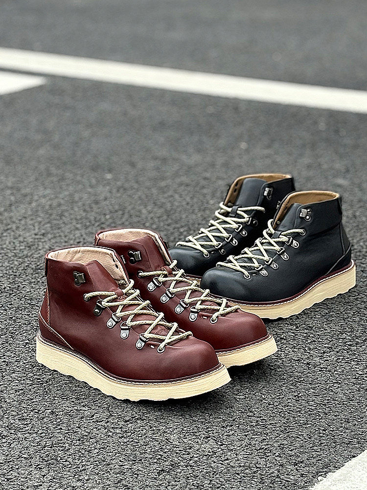 Pair of brown and black hiking boots on a gray pavement background