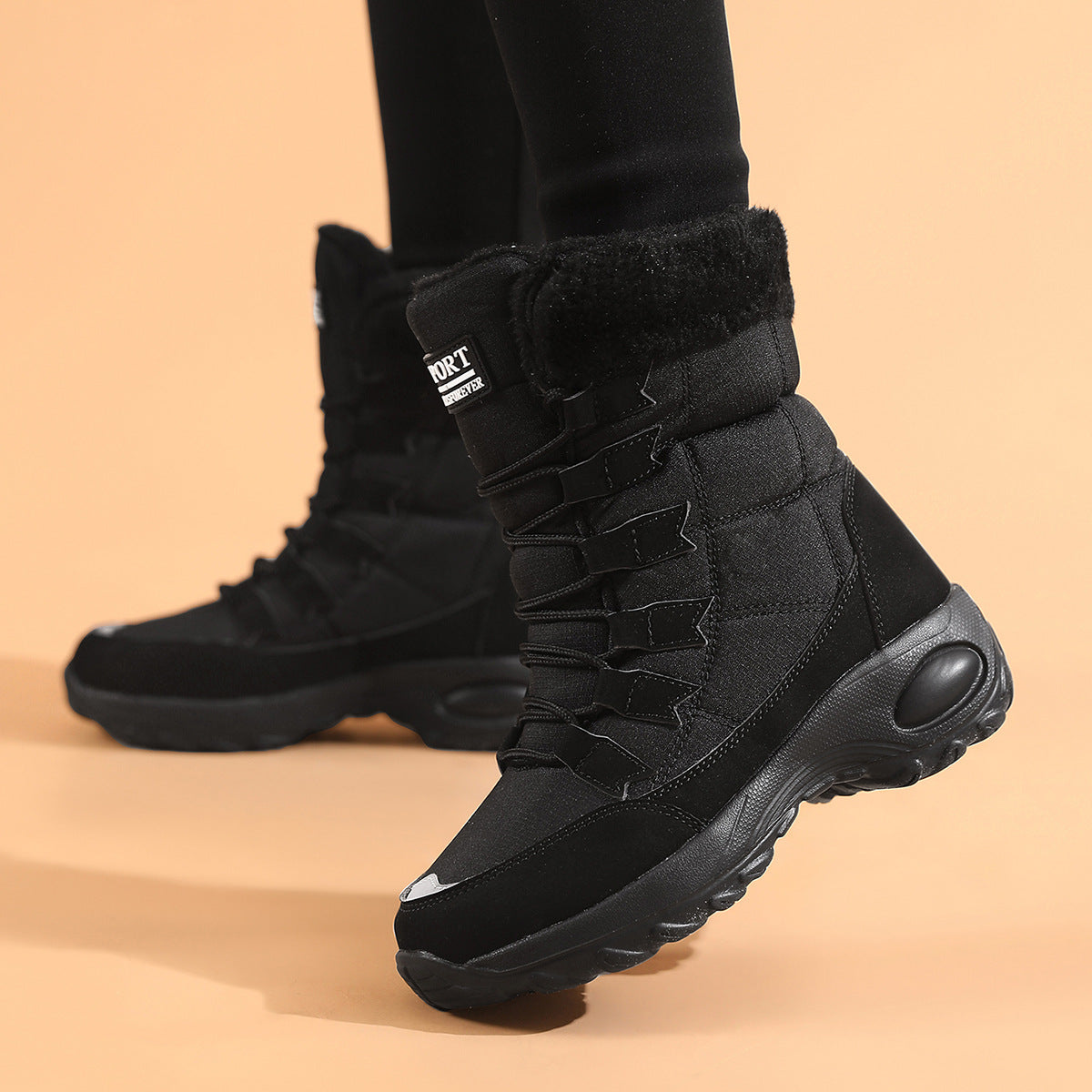 Black winter boots with brand logo on a beige background