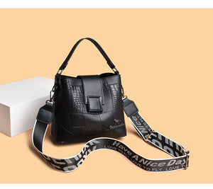 Black handbag with a branded strap on a beige background