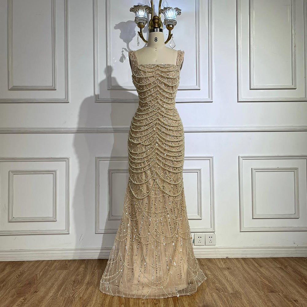 Beige evening gown on a mannequin against a white paneled wall.
