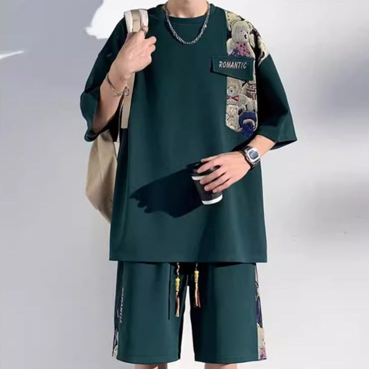Person wearing a green outfit with a colorful backpack and holding a phone on a plain background