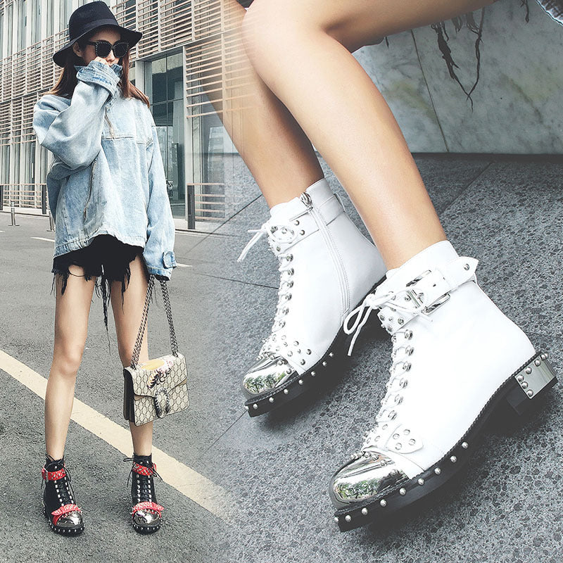 Person wearing white high-top sneakers with silver accents on a street.