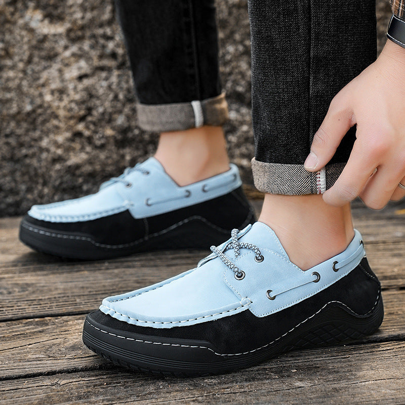Light blue loafers with black soles worn by a person on a wooden floor.