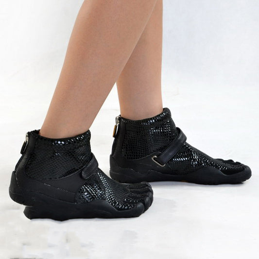 Black high-top shoes with snake skin pattern worn by a person on a white background