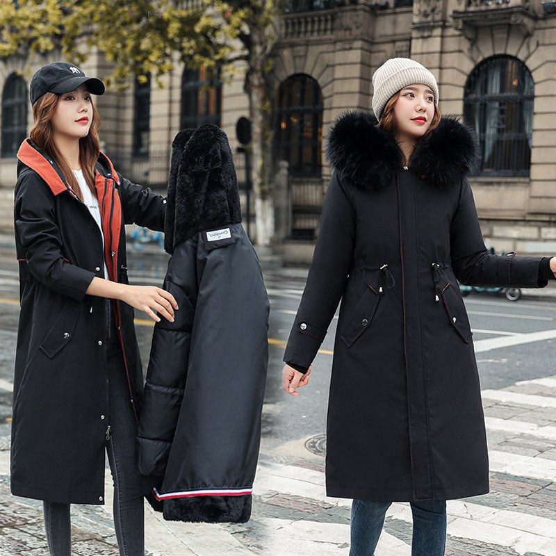 Two women wearing long black coats with fur hoods on a city street.