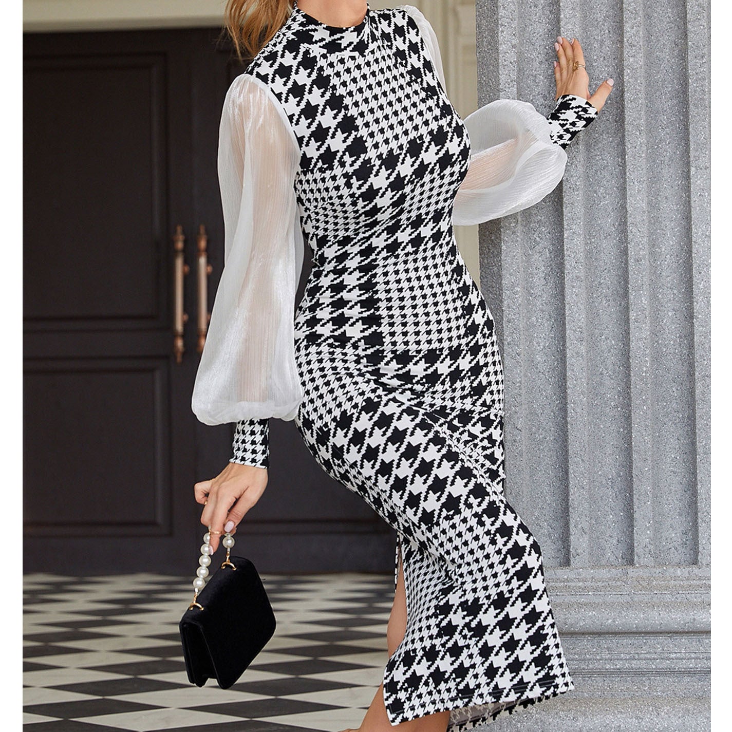 Woman wearing a black and white patterned dress with sheer sleeves, standing indoors.