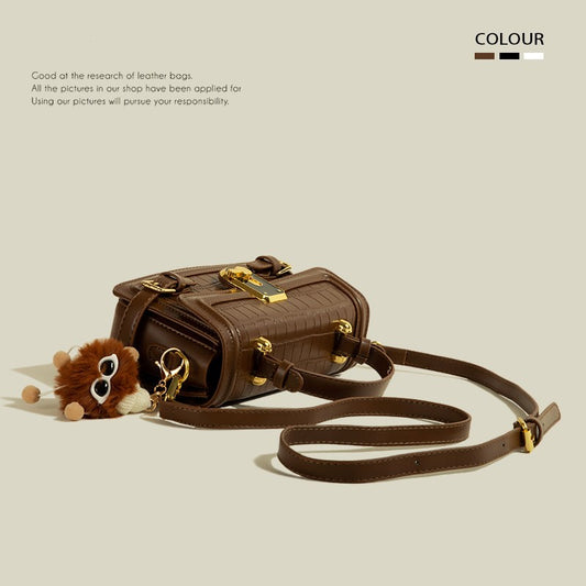 Brown leather handbag with gold accents on a beige background
