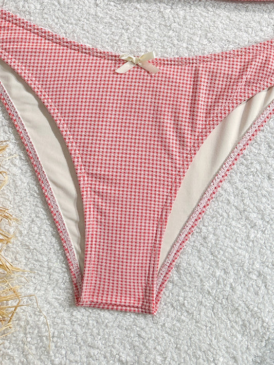 Red and white checkered bikini bottom on a textured surface