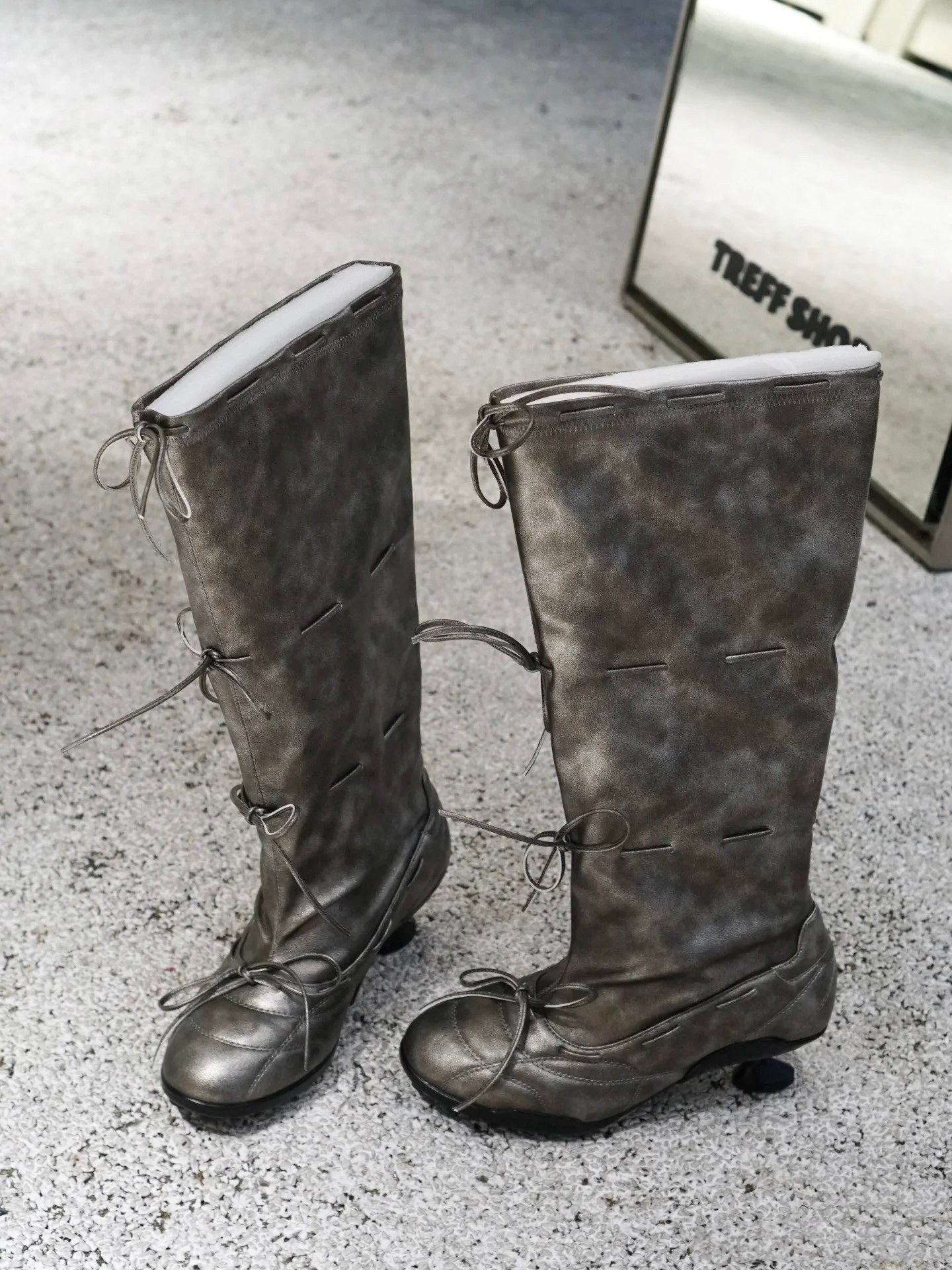 Pair of vintage-style gray knee-high boots on a textured surface.