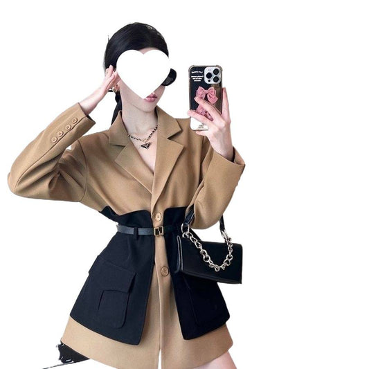 Person wearing a beige and black outfit with a phone and handbag on a white background