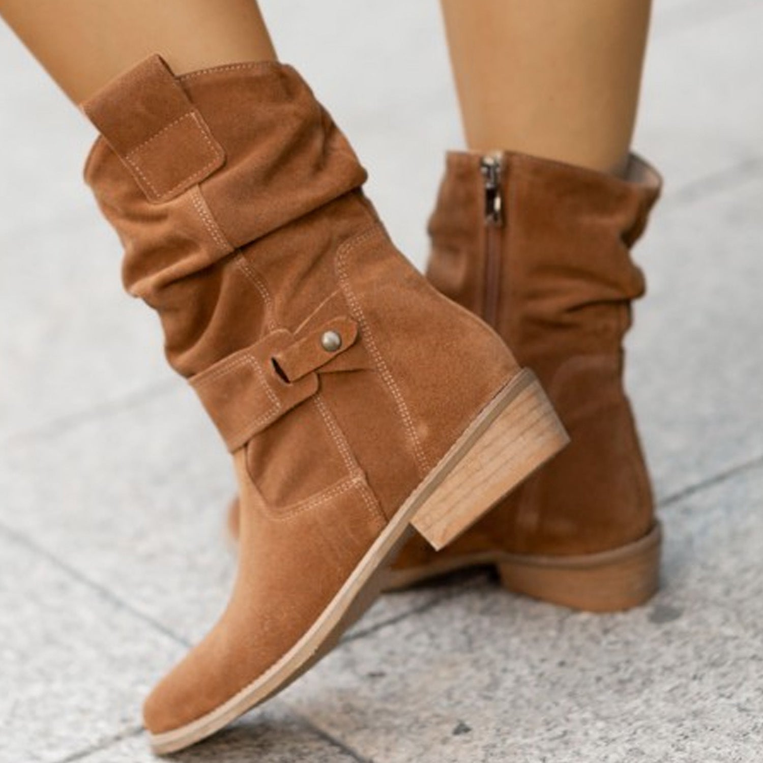 Brown suede boots with buckles on a light gray background