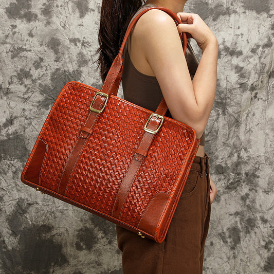 Person holding a woven brown leather handbag against a textured gray background