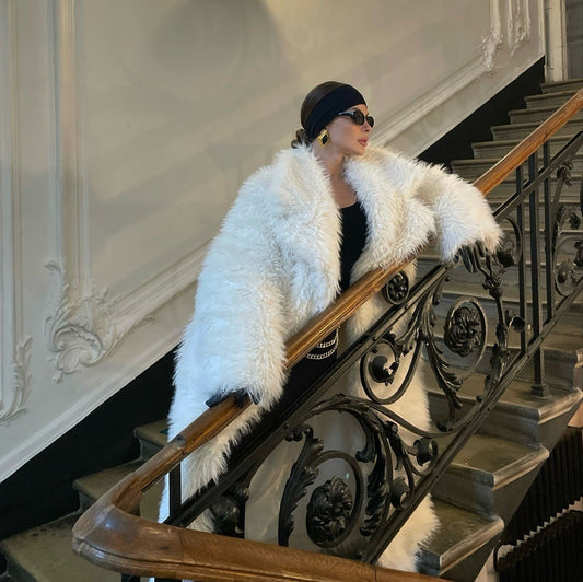 Person wearing a white fur coat standing on a staircase