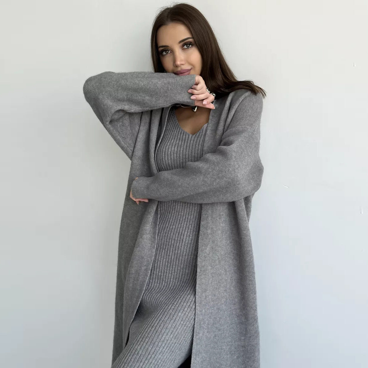 Woman wearing a long gray cardigan over a matching dress against a white background