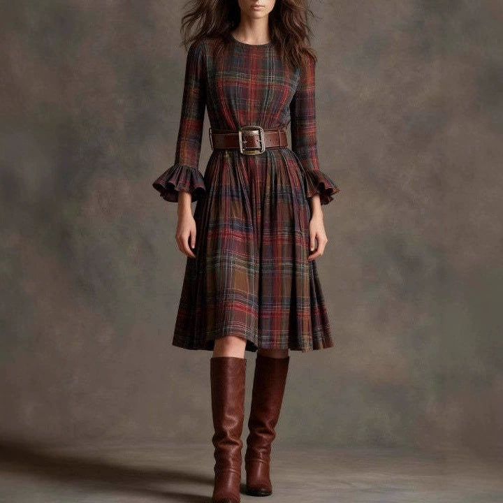 Woman wearing a plaid dress with ruffled sleeves and brown knee-high boots against a gray background by millivan