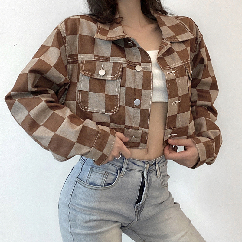 Person wearing a brown and beige checkered jacket with a white top and blue jeans on a white background