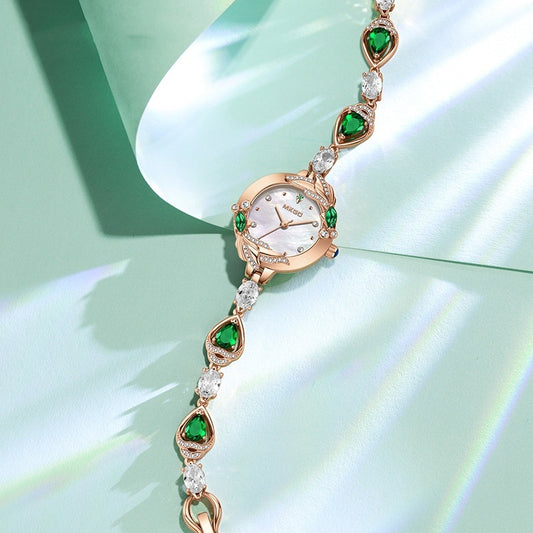 Delicate watch with green gemstones on a light green background
