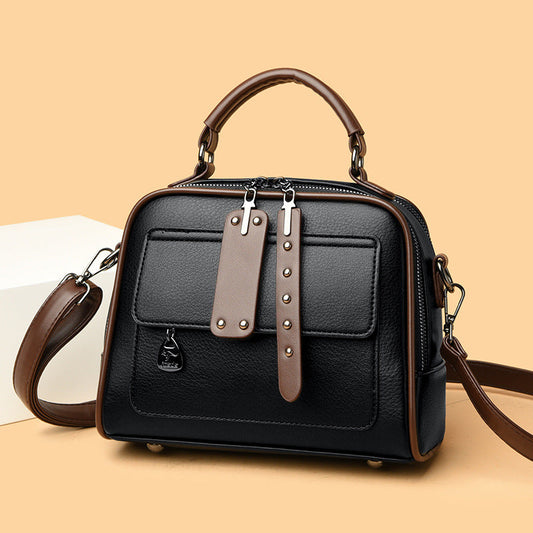 Black handbag with brown straps on a beige background