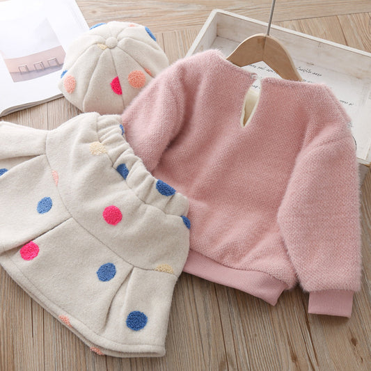 Pink fleece sweater and polka dot hat on a wooden surface