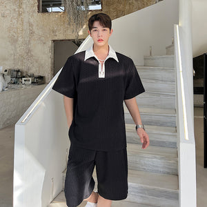 Person wearing a black outfit with a white shirt collar in an indoor setting