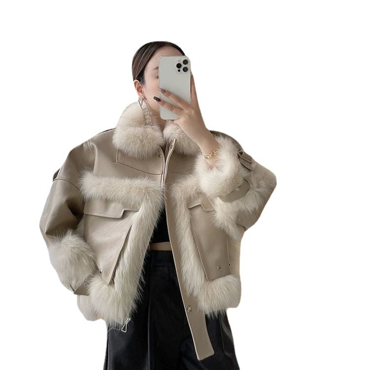 Person wearing a beige jacket with fur trim, taking a mirror selfie.