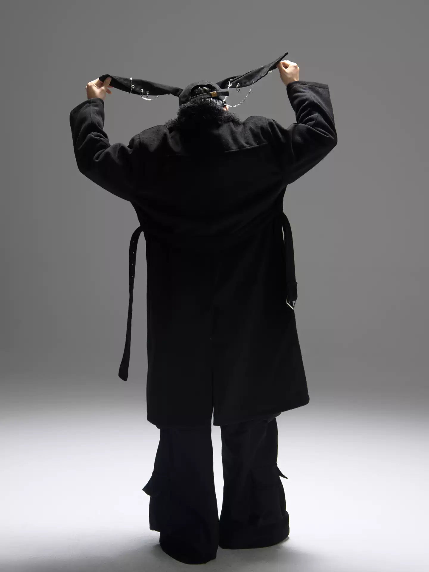 Person wearing a black robe with wide sleeves against a gray background
