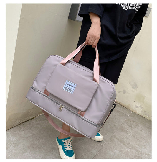 Person holding a gray duffel bag with pink straps against a plain background