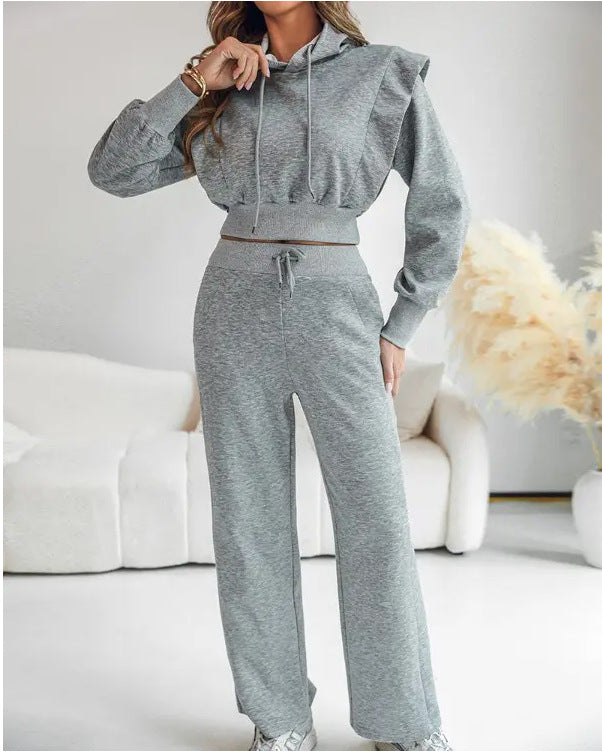 Person wearing a gray tracksuit in a minimalistic room with white sofa and decorative elements.
