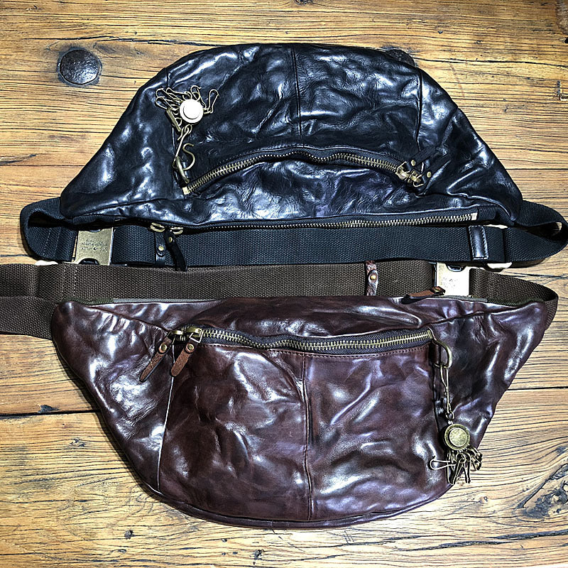 Two leather waist bags on a wooden surface