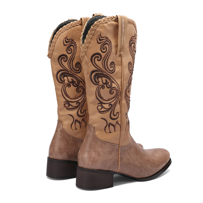 Pair of brown cowboy boots with intricate designs on a white background