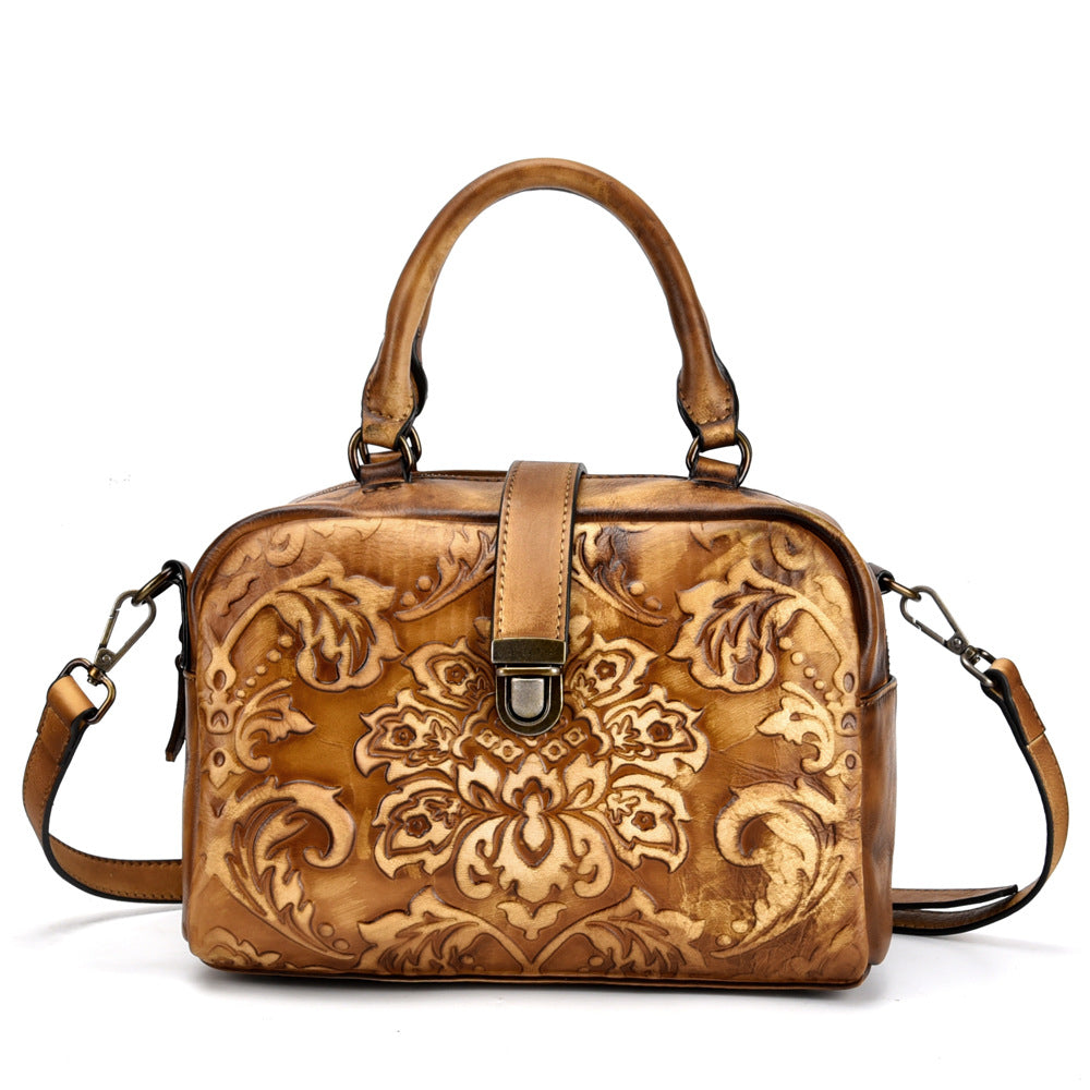 Brown leather handbag with intricate floral patterns on a white background