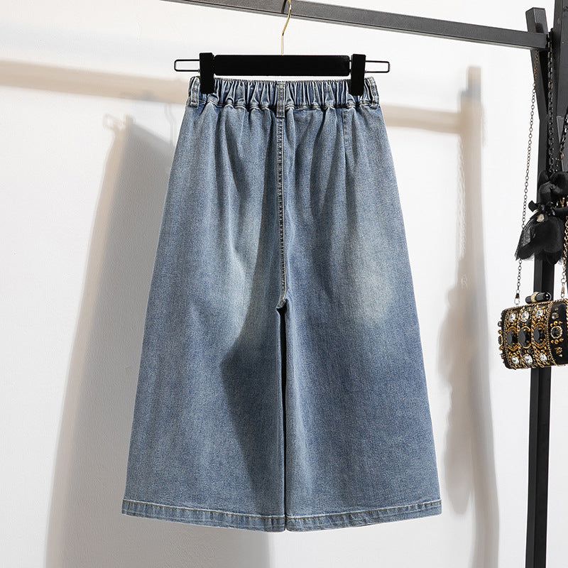 Blue denim wide-leg pants hanging on a rack against a white background