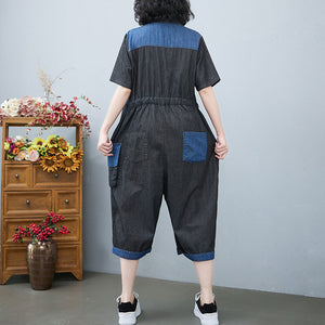 Person wearing a denim jumpsuit with blue accents in a room with a wooden dresser and flowers.