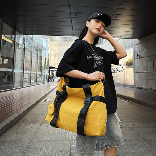 Woman holding a yellow duffel bag in an urban setting