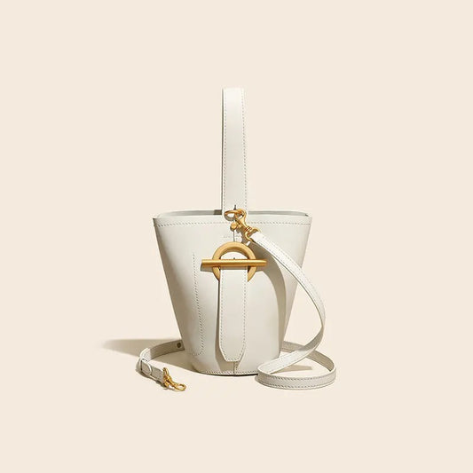 White bucket bag with gold accents on a beige background