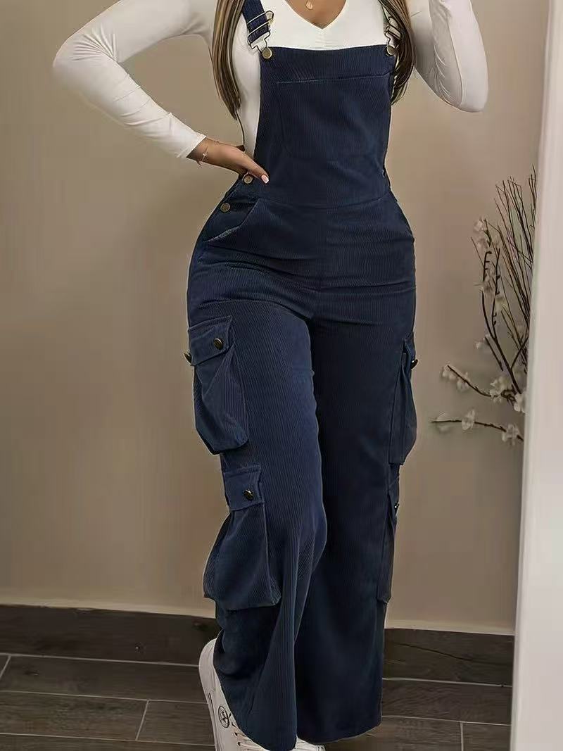 Person wearing navy blue overalls with a plain background