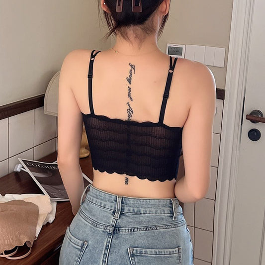 Person wearing a black scalloped-edge crop top and blue jeans indoors.