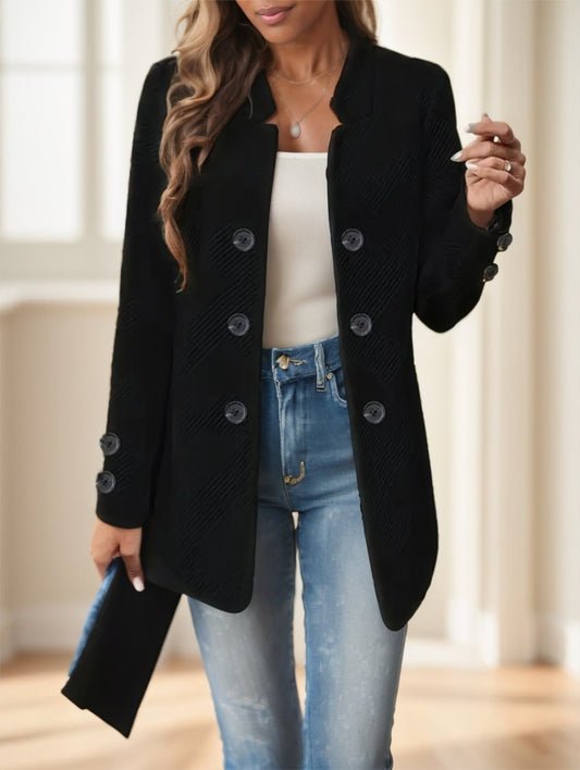 Person wearing a black coat over a white top and blue jeans indoors.