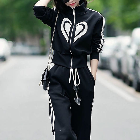 Person wearing a black tracksuit with heart designs on a blurred street background