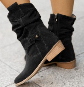 Black boots with brown soles on a light gray background
