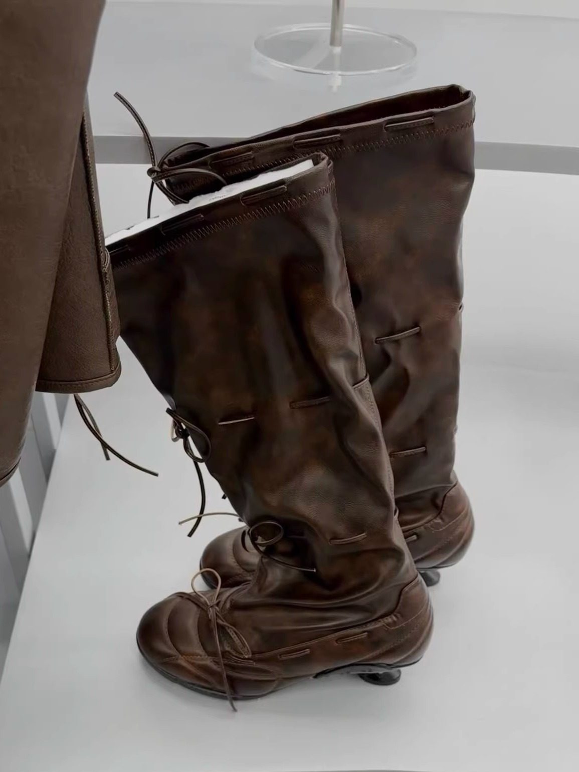 Brown knee-high boots on a white surface