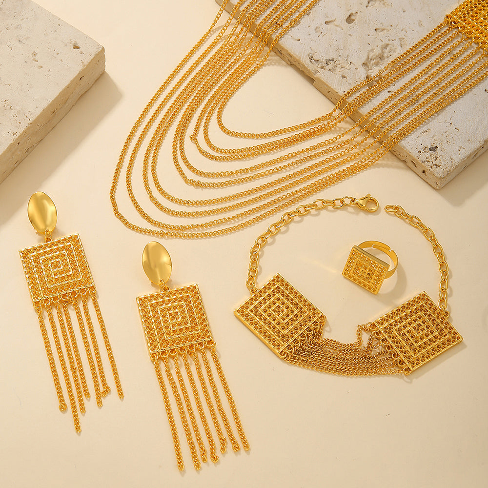 Gold jewelry set including necklace, earrings, bracelet, and ring on a beige surface.
