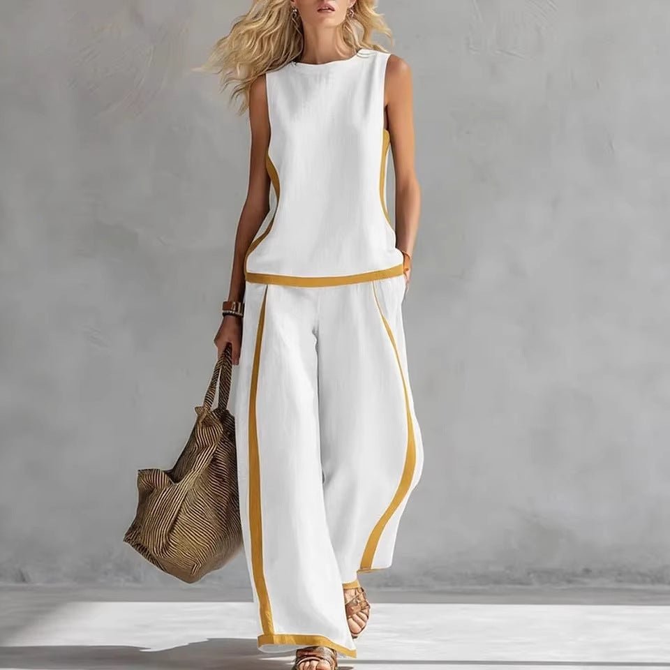 Woman wearing a white outfit with yellow accents, holding a woven bag against a gray background