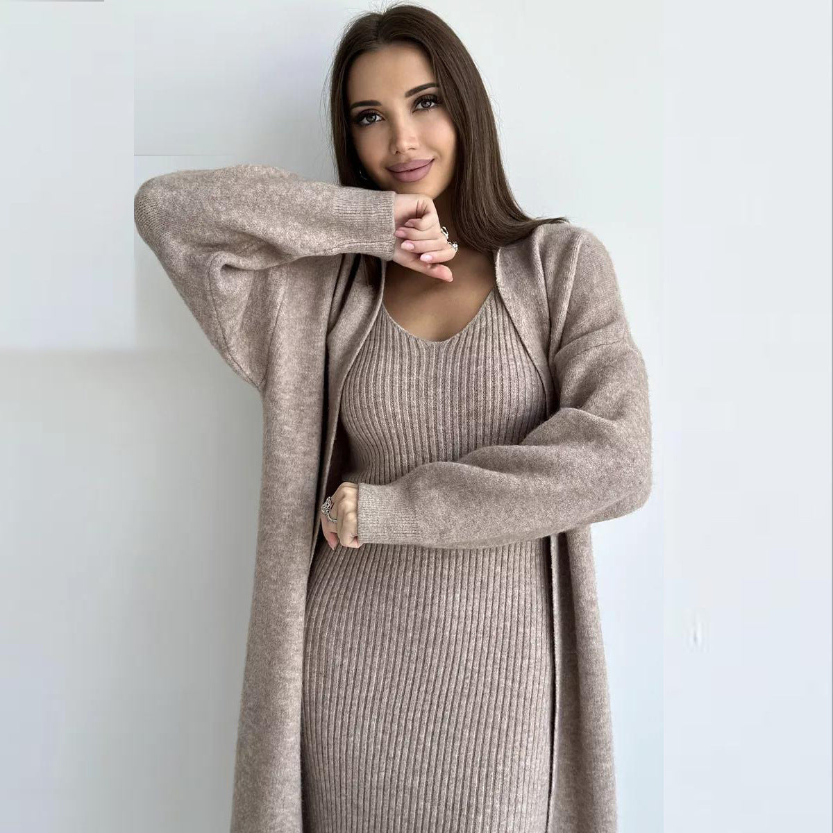 Woman wearing a long beige cardigan over a matching dress against a white background