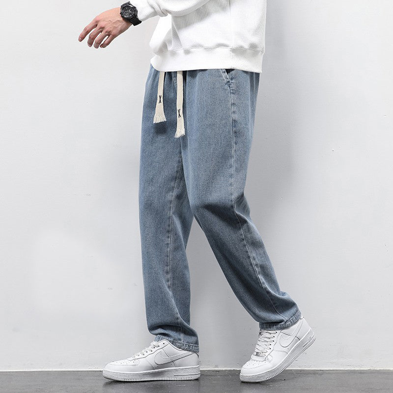 Person wearing light blue jeans and white sneakers on a plain background